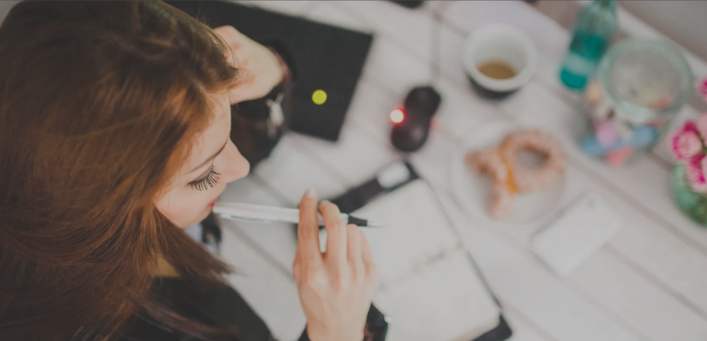 Overhead view woman working at cluttered desk