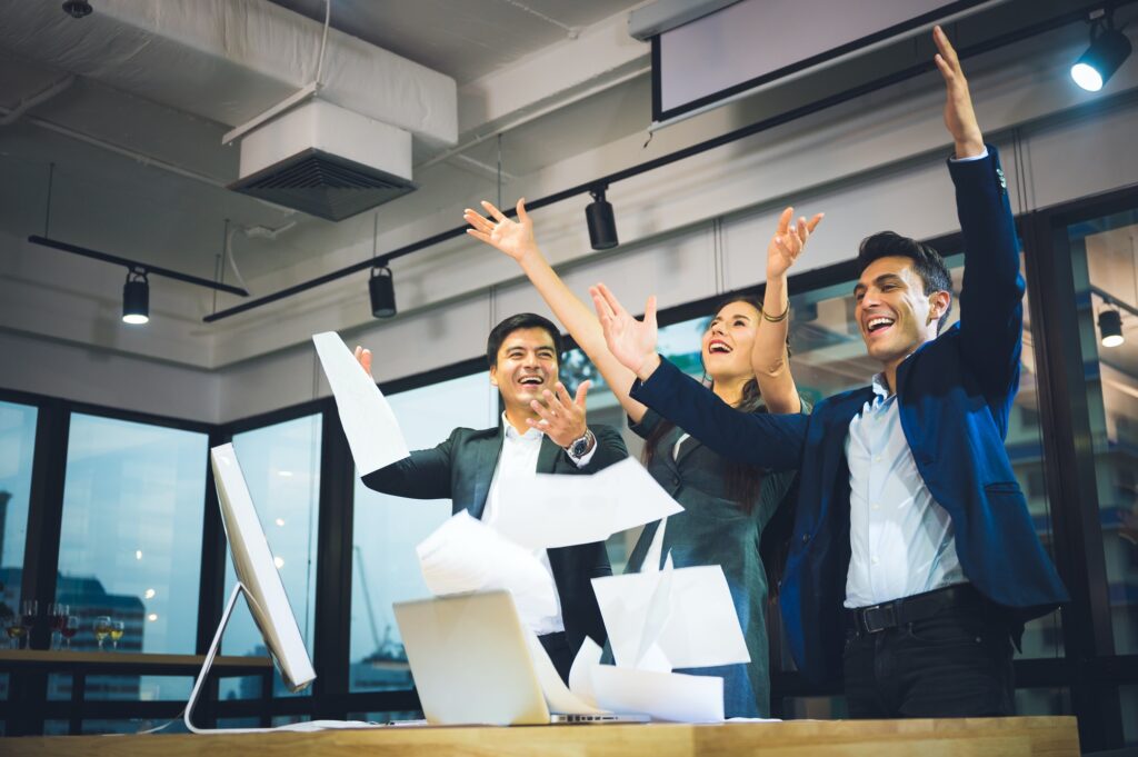 Business team celebrating success, throwing papers