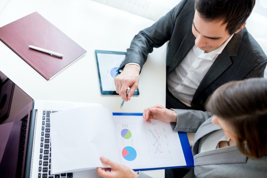Business colleagues reviewing charts on laptop and tablet