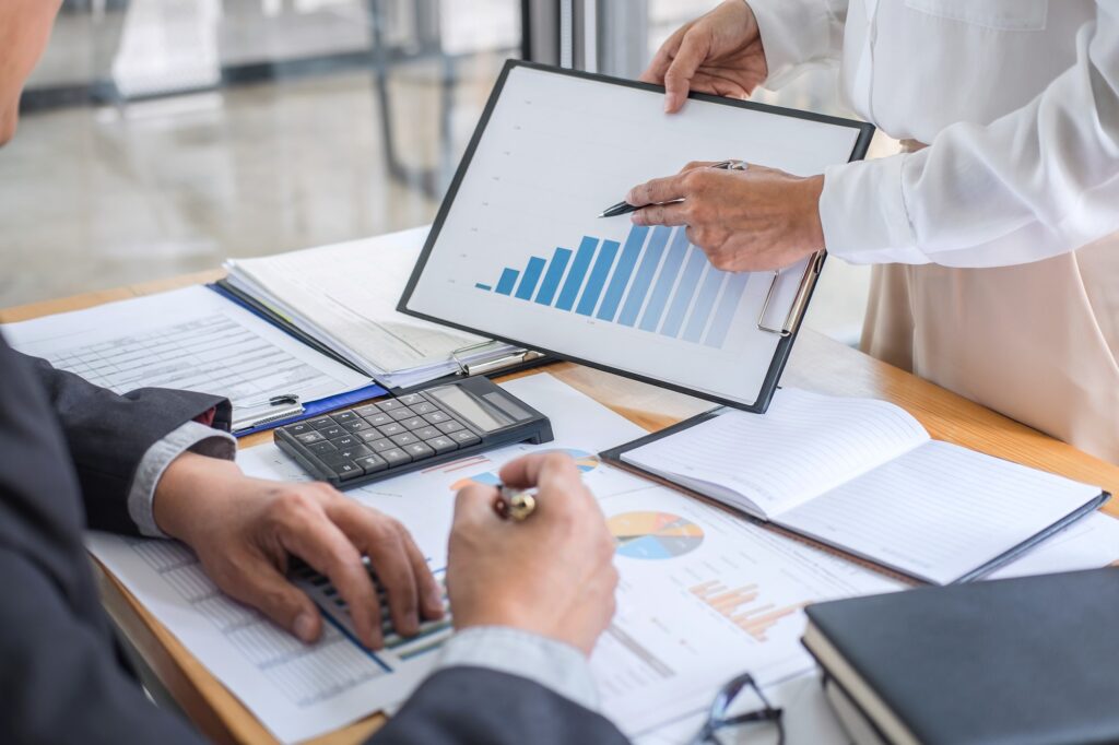 Business meeting reviewing rising bar chart