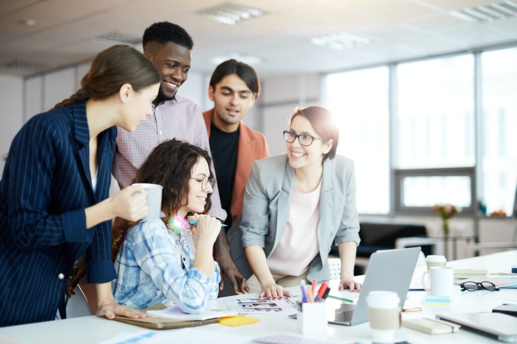 Smiling team collaborating around laptop in office