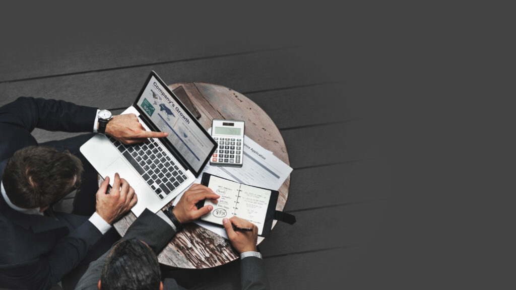 Two professionals reviewing financial documents with laptop